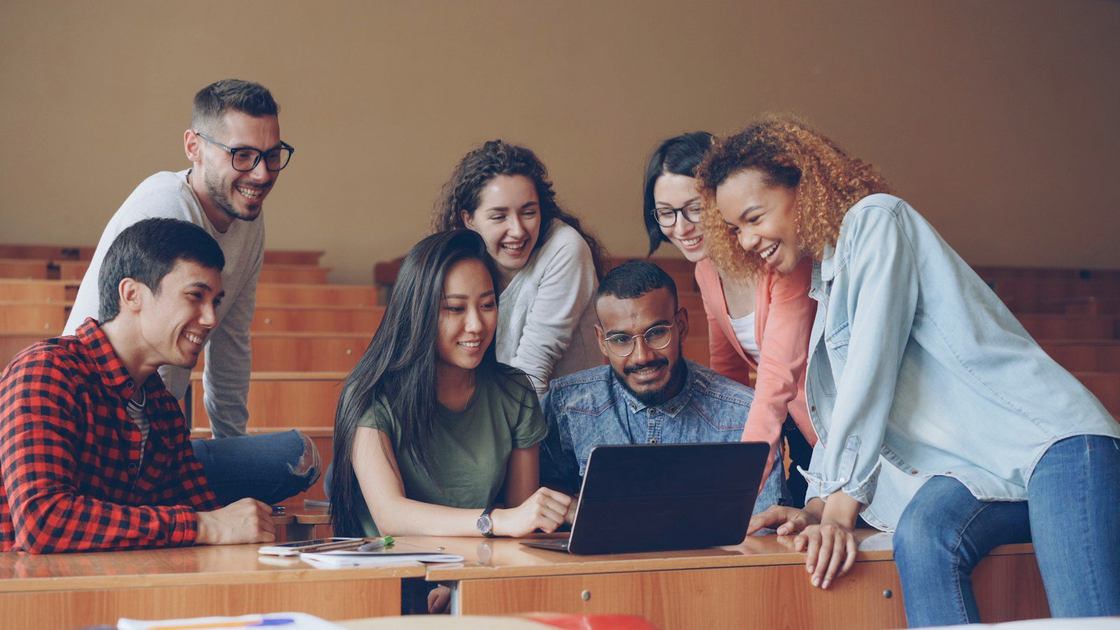 A group of students discussing a project together around a laptop.